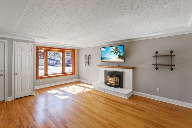 unfurnished living room with ornamental molding, a textured ceiling, baseboards, and wood finished floors