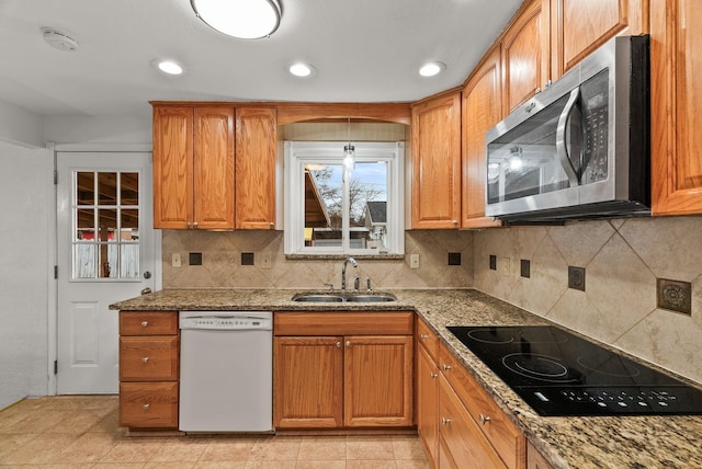 kitchen with a sink, stainless steel microwave, stone counters, black electric cooktop, and dishwasher