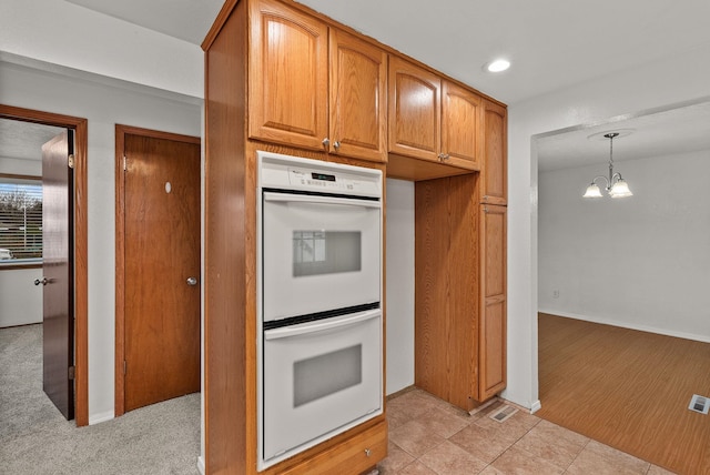 kitchen featuring white double oven, hanging light fixtures, recessed lighting, brown cabinetry, and a notable chandelier