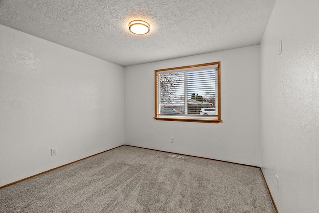 empty room with carpet flooring, a textured ceiling, baseboards, and a textured wall