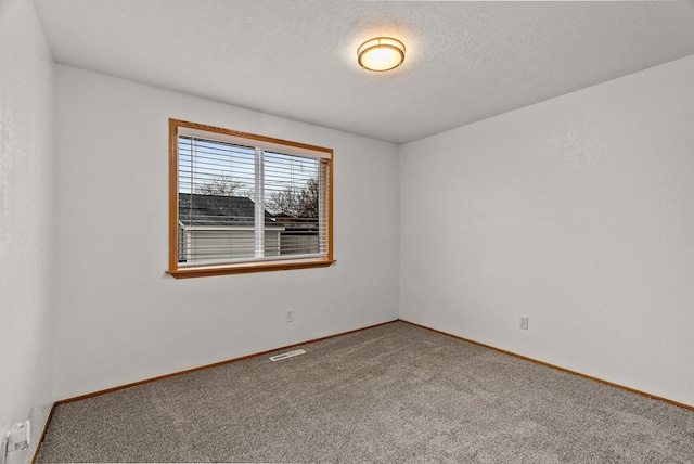 carpeted spare room featuring visible vents, baseboards, and a textured ceiling