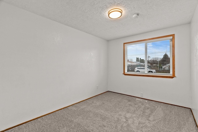 empty room with visible vents, carpet, baseboards, and a textured ceiling