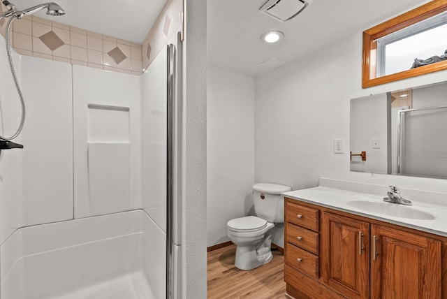 bathroom featuring a shower stall, toilet, wood finished floors, a textured wall, and vanity