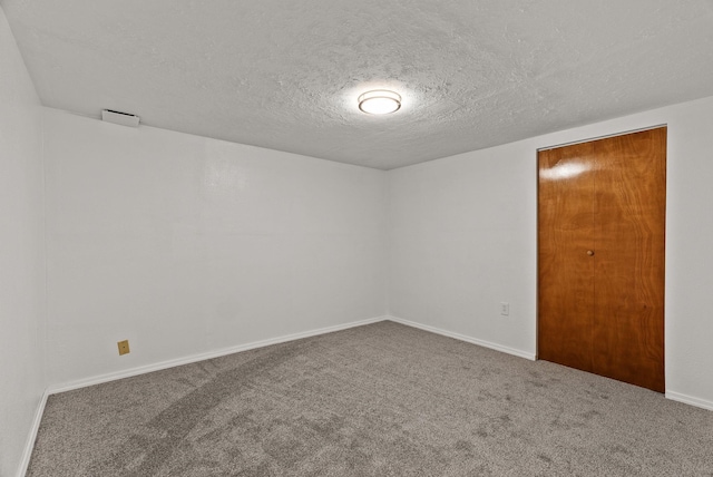 empty room featuring carpet, baseboards, and a textured ceiling