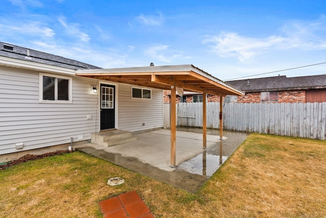 rear view of house with entry steps, a patio, a yard, and fence