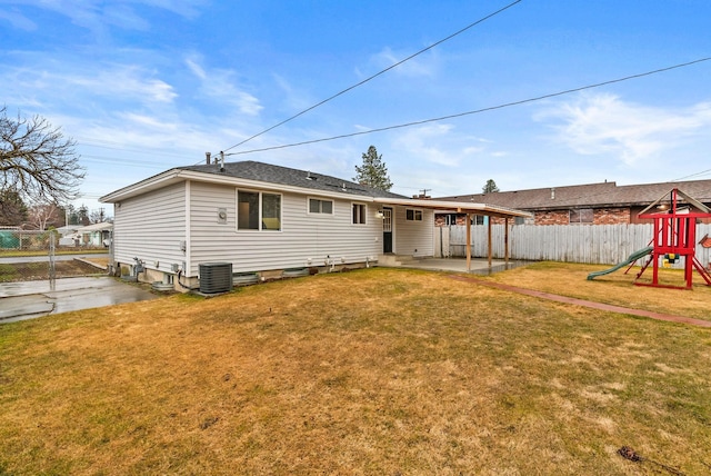 rear view of house with a lawn, fence, a playground, central AC unit, and a patio area