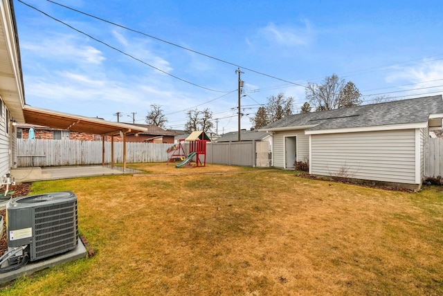 view of yard with a playground, central AC unit, a fenced backyard, an outbuilding, and a patio