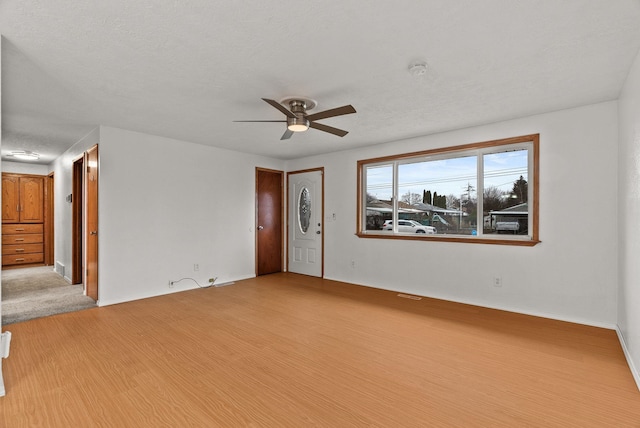 spare room with a textured ceiling, a ceiling fan, and wood finished floors