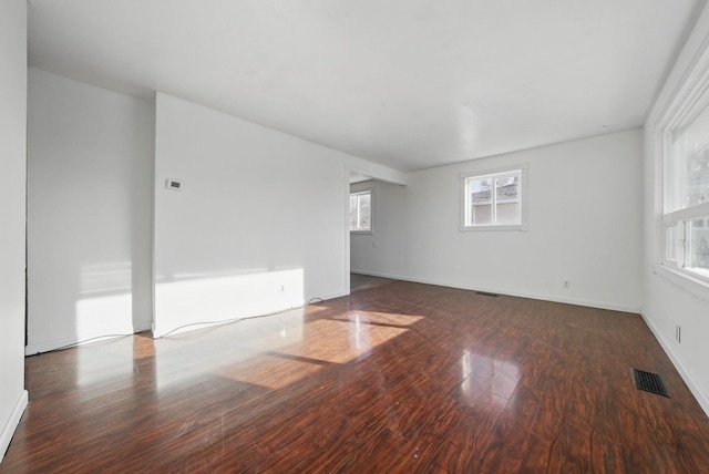 empty room featuring visible vents, baseboards, and wood finished floors