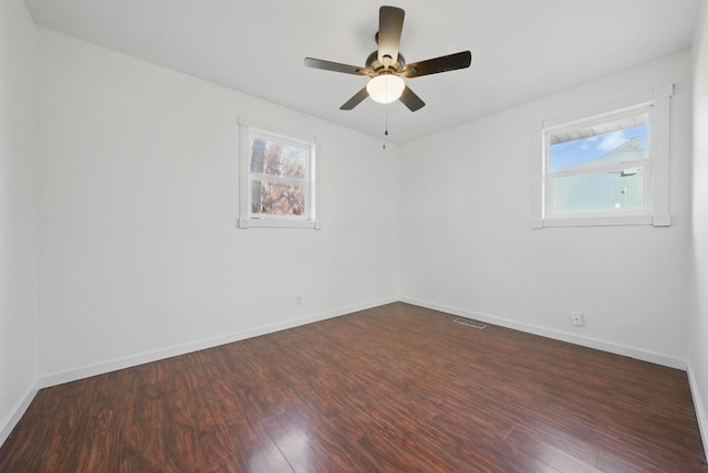 empty room featuring dark wood finished floors, visible vents, and baseboards