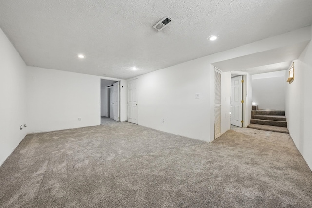 unfurnished room featuring visible vents, recessed lighting, stairs, a textured ceiling, and light colored carpet