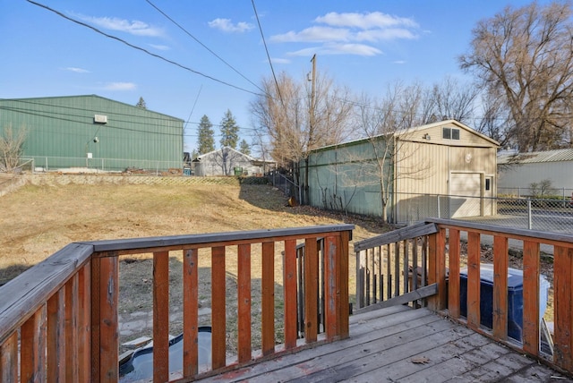 wooden deck with a garage, an outbuilding, and fence