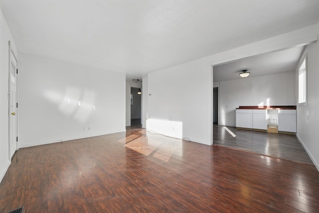 unfurnished living room with visible vents, wood finished floors, and baseboards