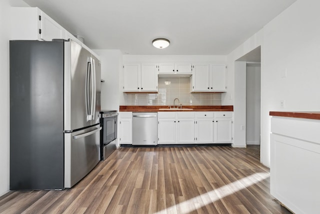 kitchen with a sink, stainless steel appliances, white cabinets, and butcher block counters