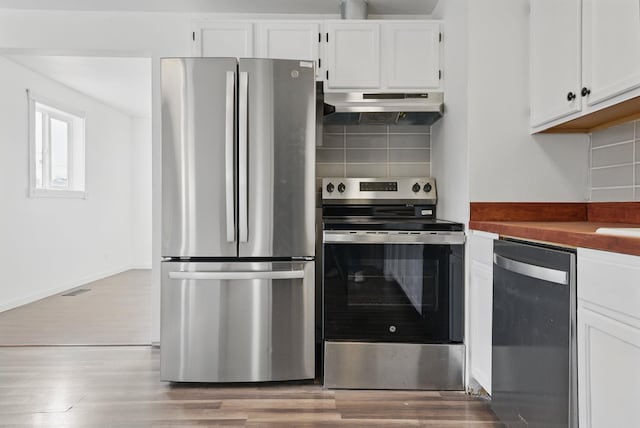 kitchen featuring white cabinets, tasteful backsplash, under cabinet range hood, and stainless steel appliances