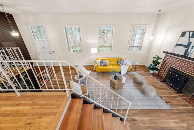 living area featuring a wealth of natural light, baseboard heating, stairs, and wood finished floors