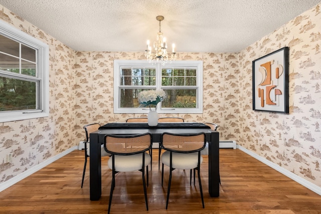 dining area with a chandelier, a textured ceiling, wallpapered walls, and wood finished floors