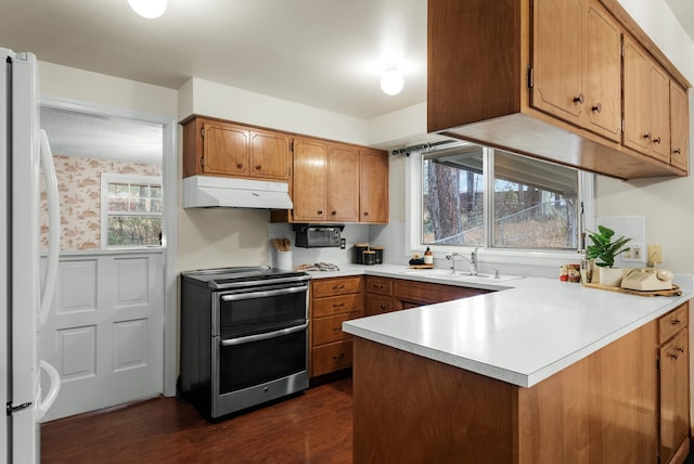 kitchen featuring under cabinet range hood, double oven range, a sink, freestanding refrigerator, and wallpapered walls