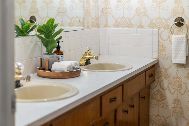 bathroom featuring wallpapered walls, double vanity, and a sink