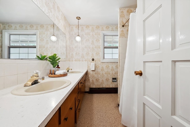 bathroom with wallpapered walls, double vanity, curtained shower, and a sink