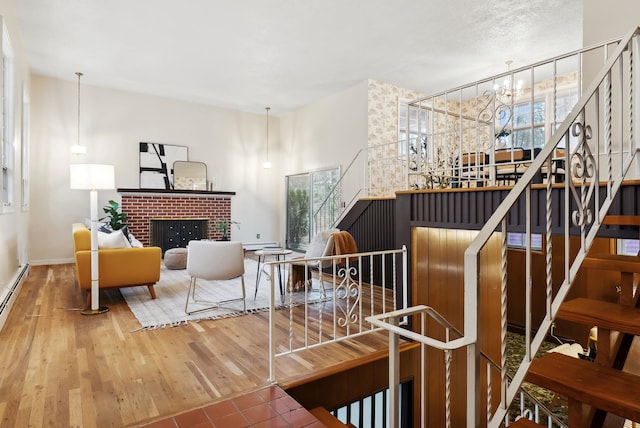 living area featuring plenty of natural light, a brick fireplace, wood finished floors, and an inviting chandelier