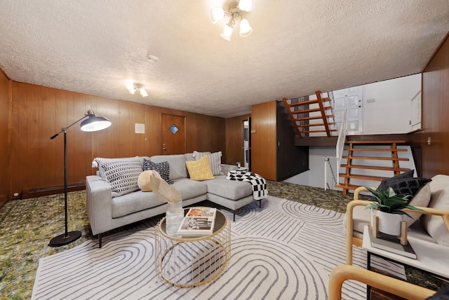 living area with a textured ceiling, wood walls, and stairs