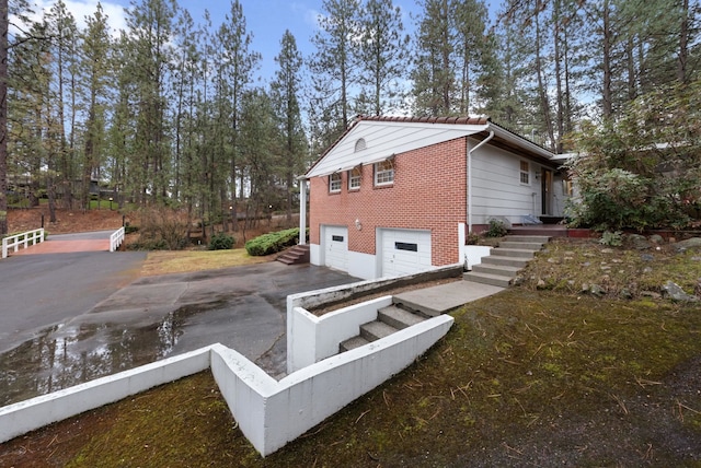 rear view of house with aphalt driveway, an attached garage, and brick siding