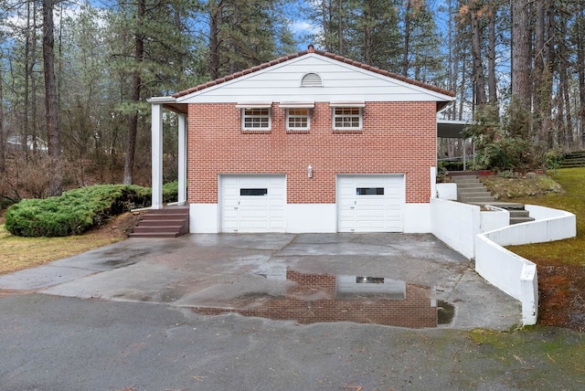 view of side of home with a garage, brick siding, and driveway