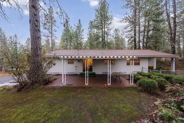 rear view of property featuring a lawn, a tiled roof, a patio, and fence