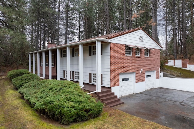 view of front of home with aphalt driveway, an attached garage, and a chimney