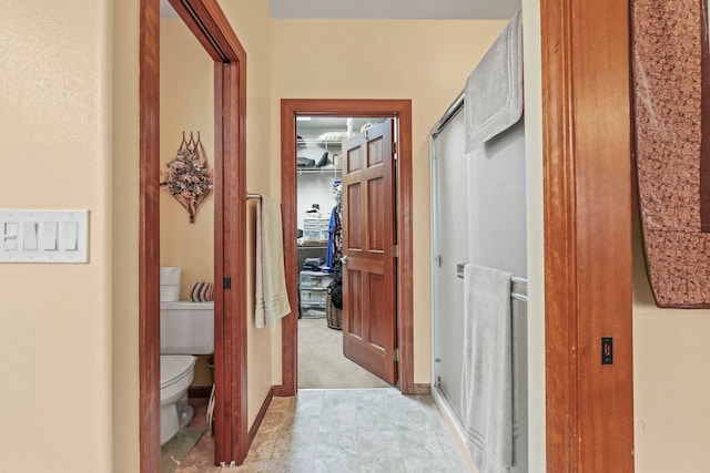 corridor featuring baseboards and light colored carpet