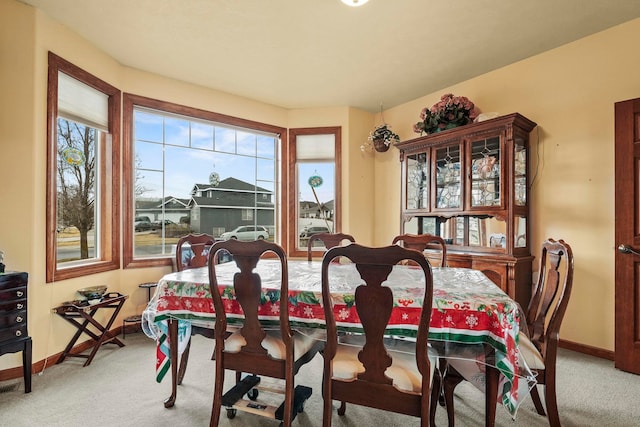 dining area featuring baseboards and light colored carpet