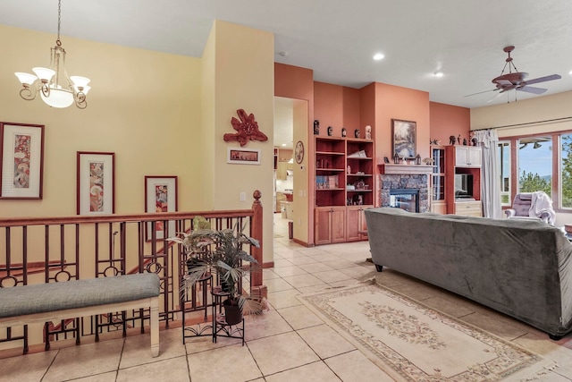 living room with recessed lighting, a stone fireplace, light tile patterned flooring, and ceiling fan with notable chandelier