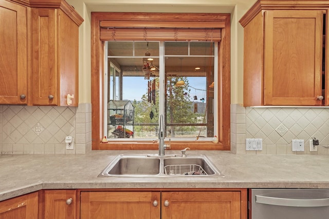 kitchen featuring brown cabinets, dishwasher, light countertops, and a sink