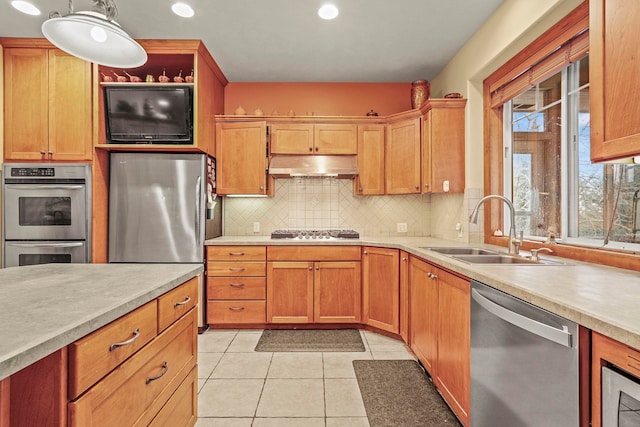 kitchen with under cabinet range hood, stainless steel appliances, light countertops, and a sink