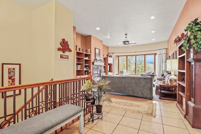 interior space with light tile patterned floors, a stone fireplace, ceiling fan, and recessed lighting