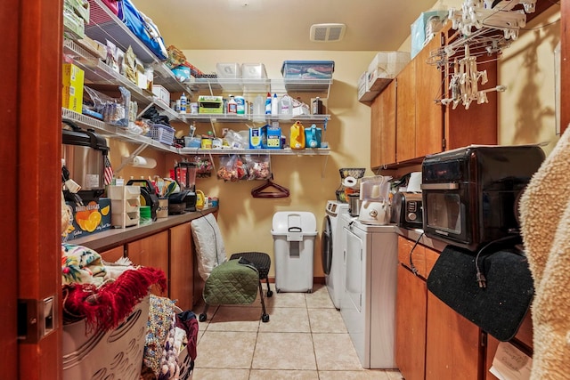 washroom with light tile patterned floors, laundry area, washing machine and dryer, and visible vents