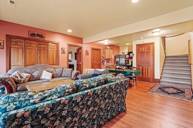 living room featuring recessed lighting, visible vents, light wood-style flooring, and stairway