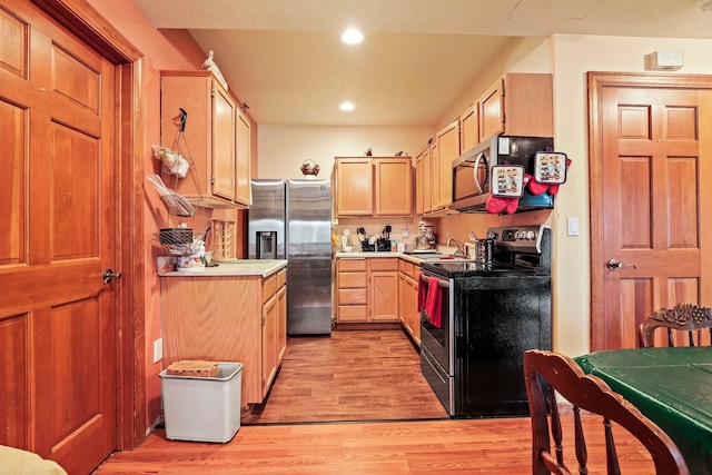 kitchen with light wood finished floors, light brown cabinets, light countertops, recessed lighting, and stainless steel appliances