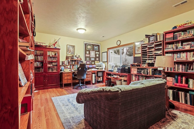 home office featuring visible vents, a textured ceiling, and wood finished floors