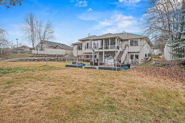 rear view of property featuring stairway, a lawn, and a sunroom