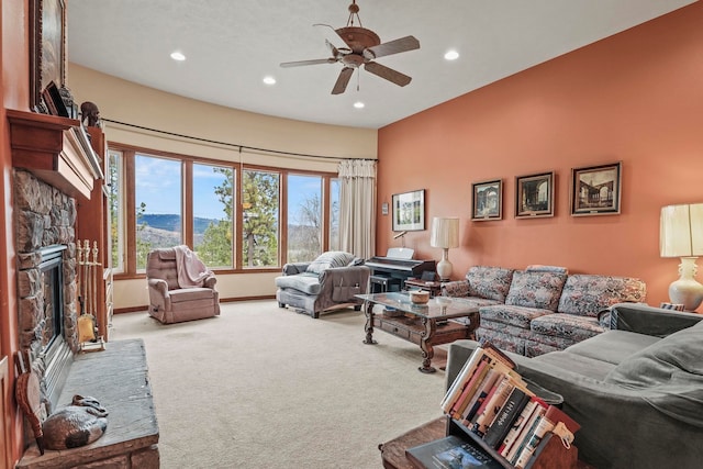 carpeted living room featuring a stone fireplace, recessed lighting, baseboards, and ceiling fan