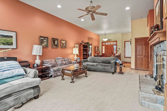 living area featuring light tile patterned floors, a ceiling fan, recessed lighting, a stone fireplace, and light colored carpet