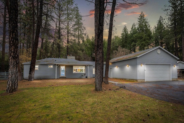 ranch-style house featuring a chimney, driveway, a front yard, and an outdoor structure