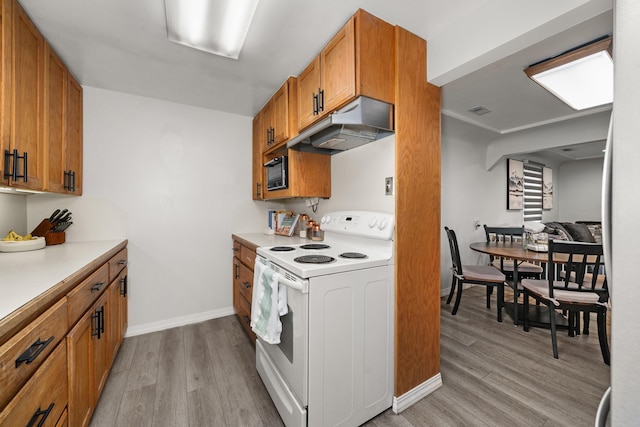 kitchen with under cabinet range hood, brown cabinetry, light wood-type flooring, and white electric range