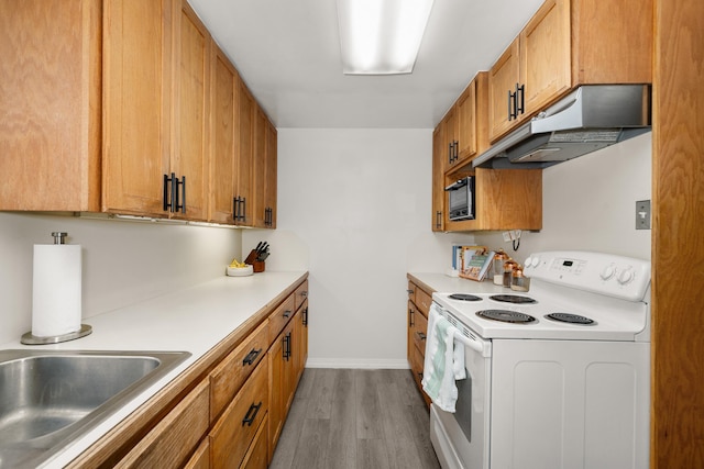 kitchen with wood finished floors, light countertops, electric stove, under cabinet range hood, and brown cabinets