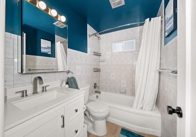 full bathroom with wood finished floors, visible vents, shower / tub combo, tile walls, and toilet