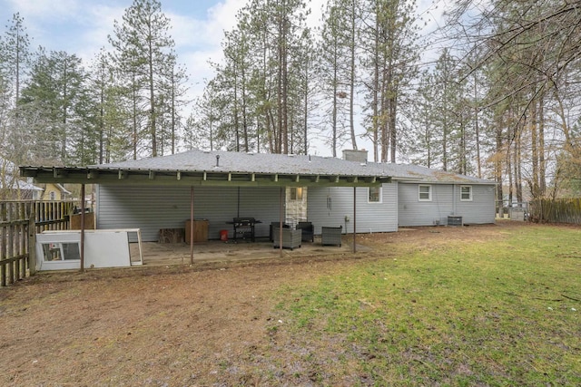 rear view of property with cooling unit, fence, a lawn, and a chimney