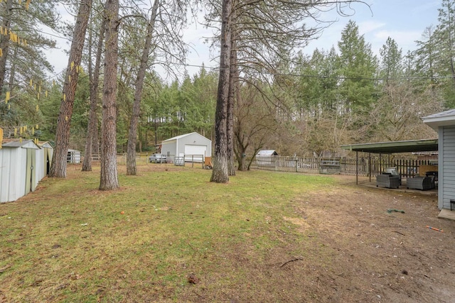 view of yard featuring an outbuilding, fence, and a shed