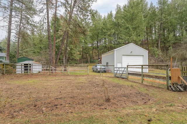 view of yard with a detached garage, an outbuilding, and fence